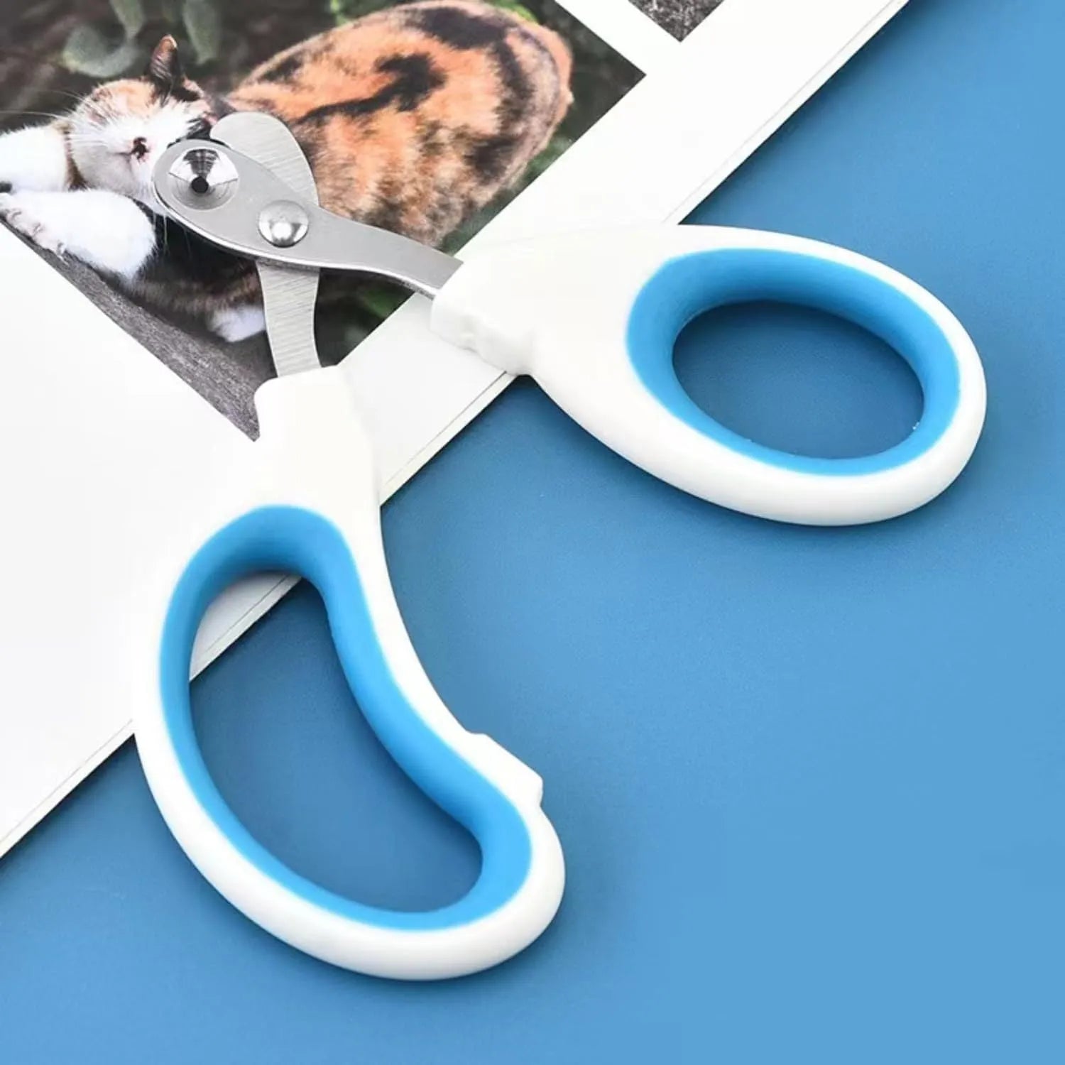 Blue pet nail clippers with circular cut hole and non-slip grip handles on a white background