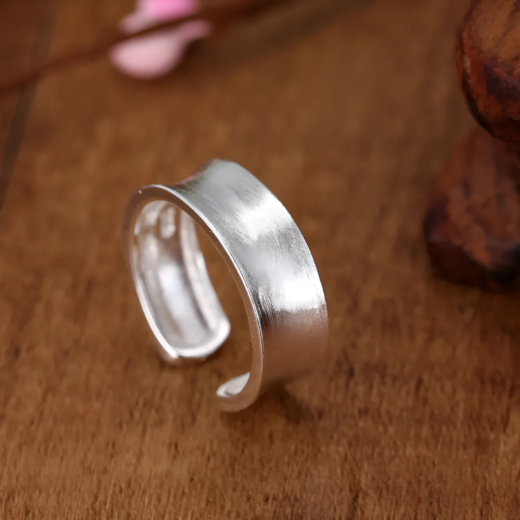 Geometric open ring with adjustable size in frosted sterling silver on a grey background.
