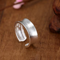 Geometric open ring with adjustable size in frosted sterling silver on a grey background.