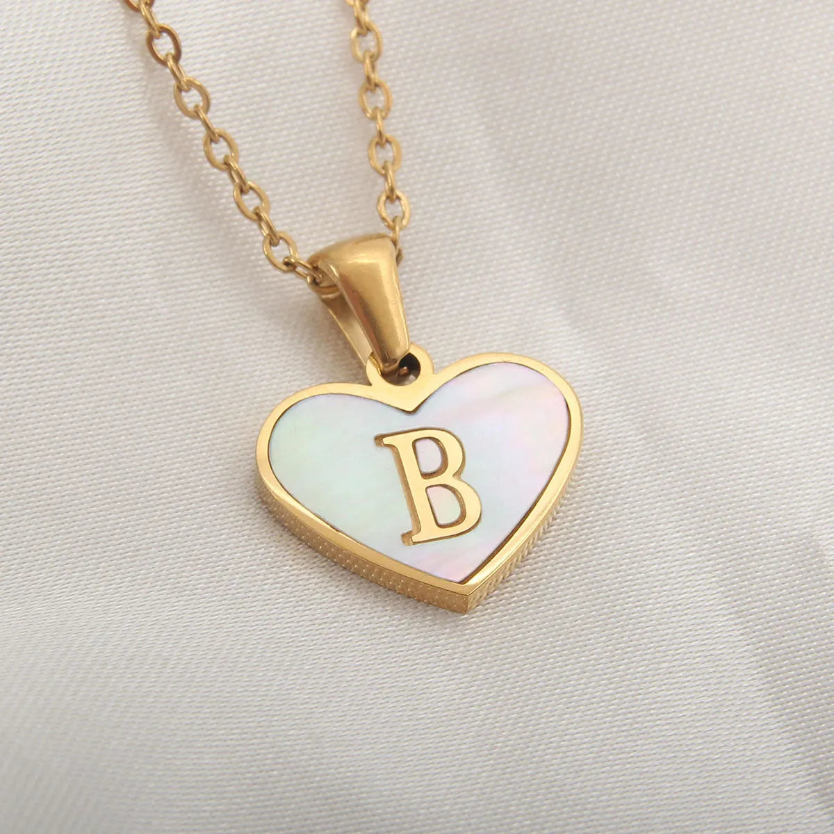 Gold plated heart-shaped white shell pendant personalised initial necklace on a stainless steel chain.