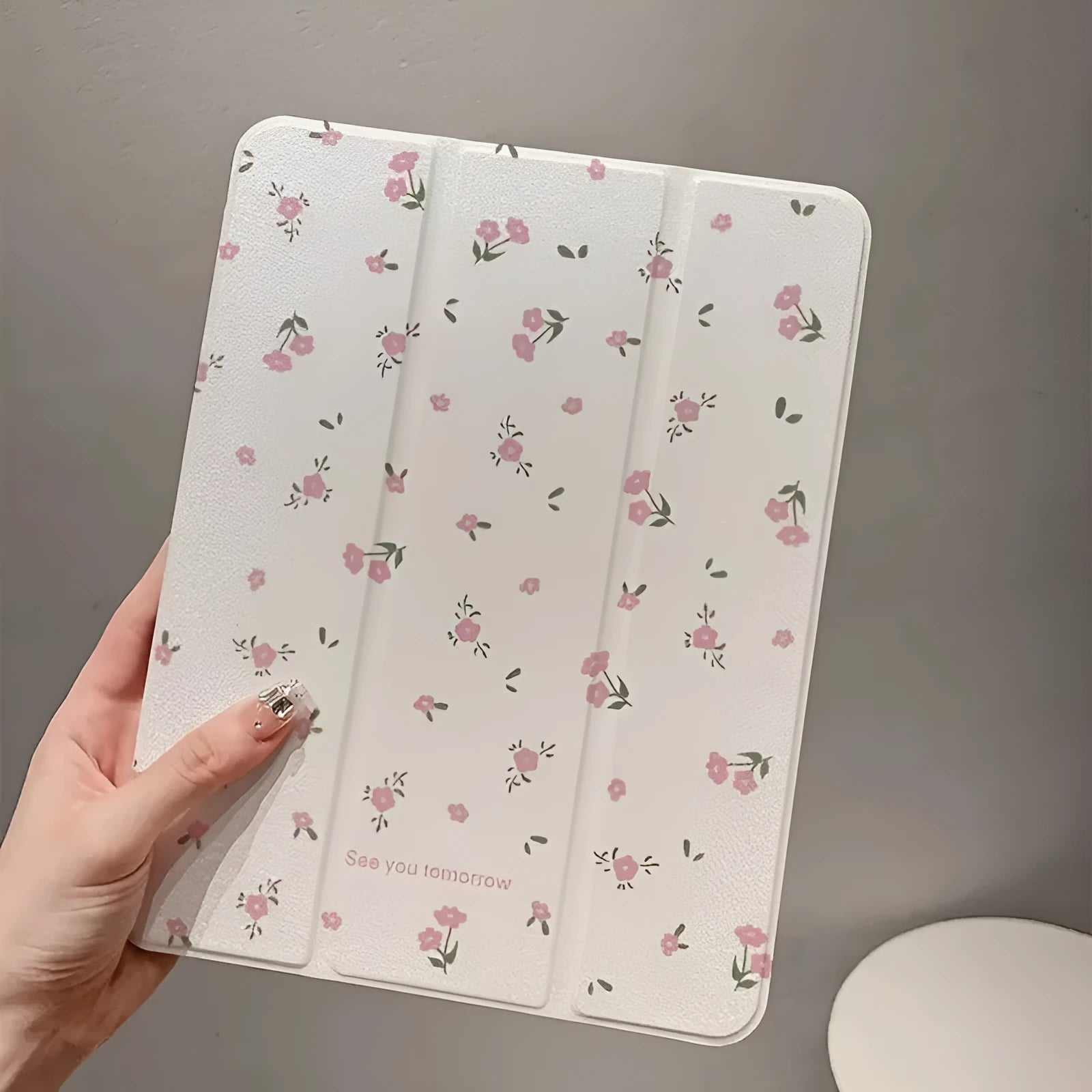Clear tri-fold iPad case with floral design, shown in stand mode.