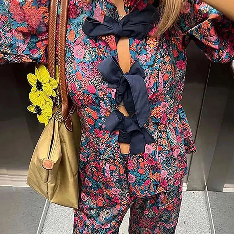 Women's floral print tie-neck trouser suit with puff sleeves, shown in the picture colour.