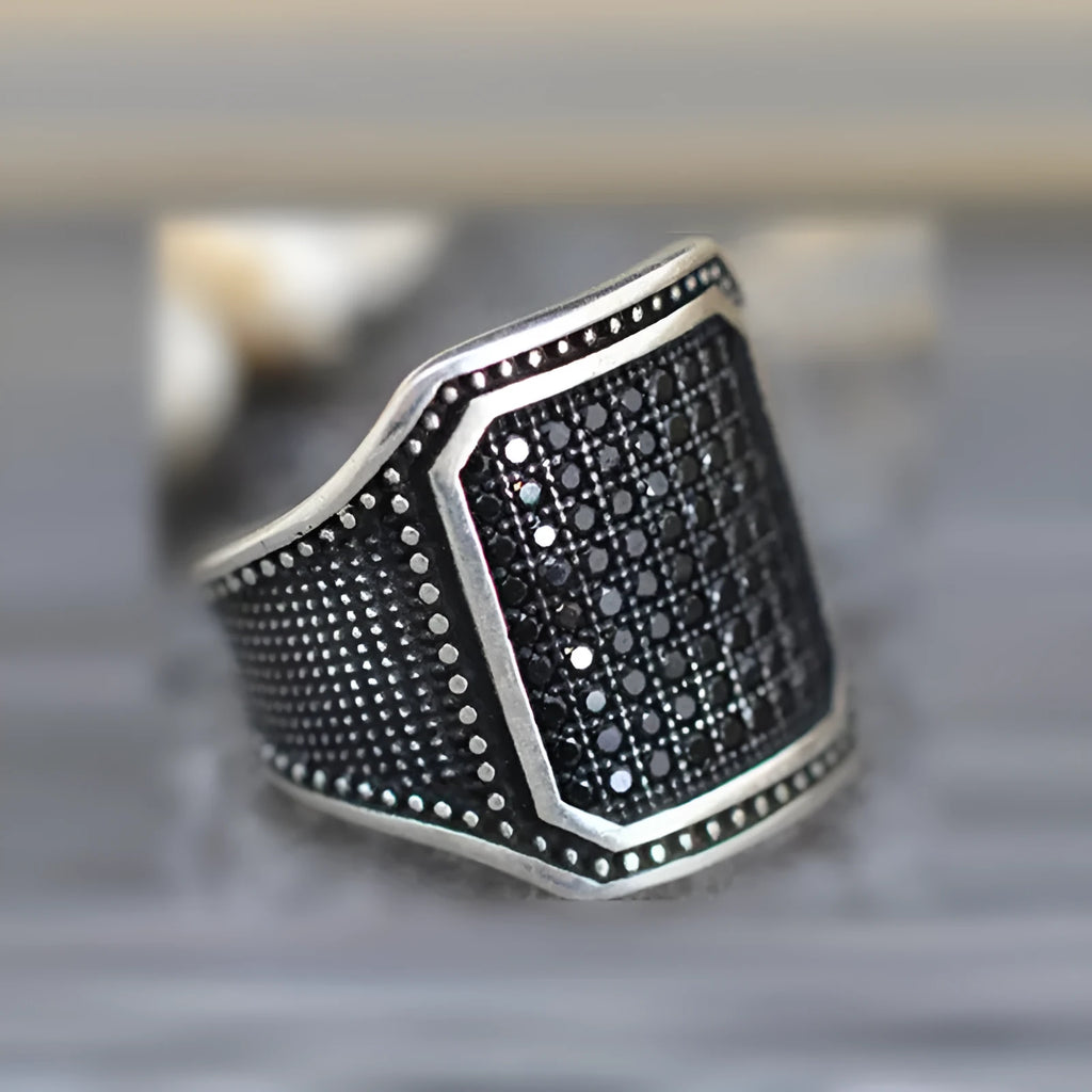 Black alloy ring with copper inlay and zircon detail on a finger, showing unisex design.