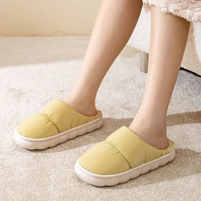 Blue down cotton indoor slippers with thick rubber sole and plush lining, shown on a wooden floor.