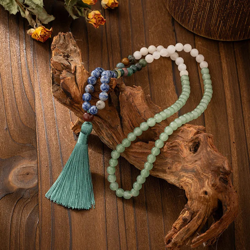 Long natural stone beaded sweater chain necklace and matching bracelet in bohemian style on a grey background.