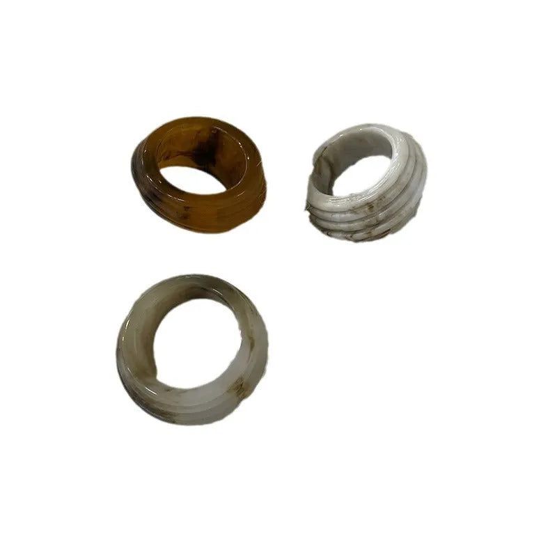 Geometric irregular resin wide ring in brown and white colours on a plain background.