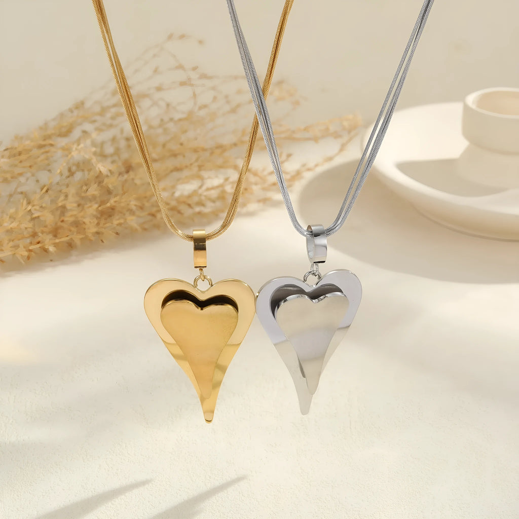 Close-up of a women's stainless steel necklace with a geometric double heart and snake bones chain design.