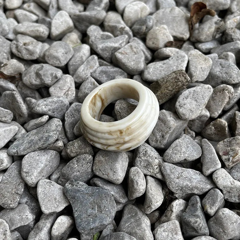 Geometric irregular resin wide ring in brown and white colours on a plain background.