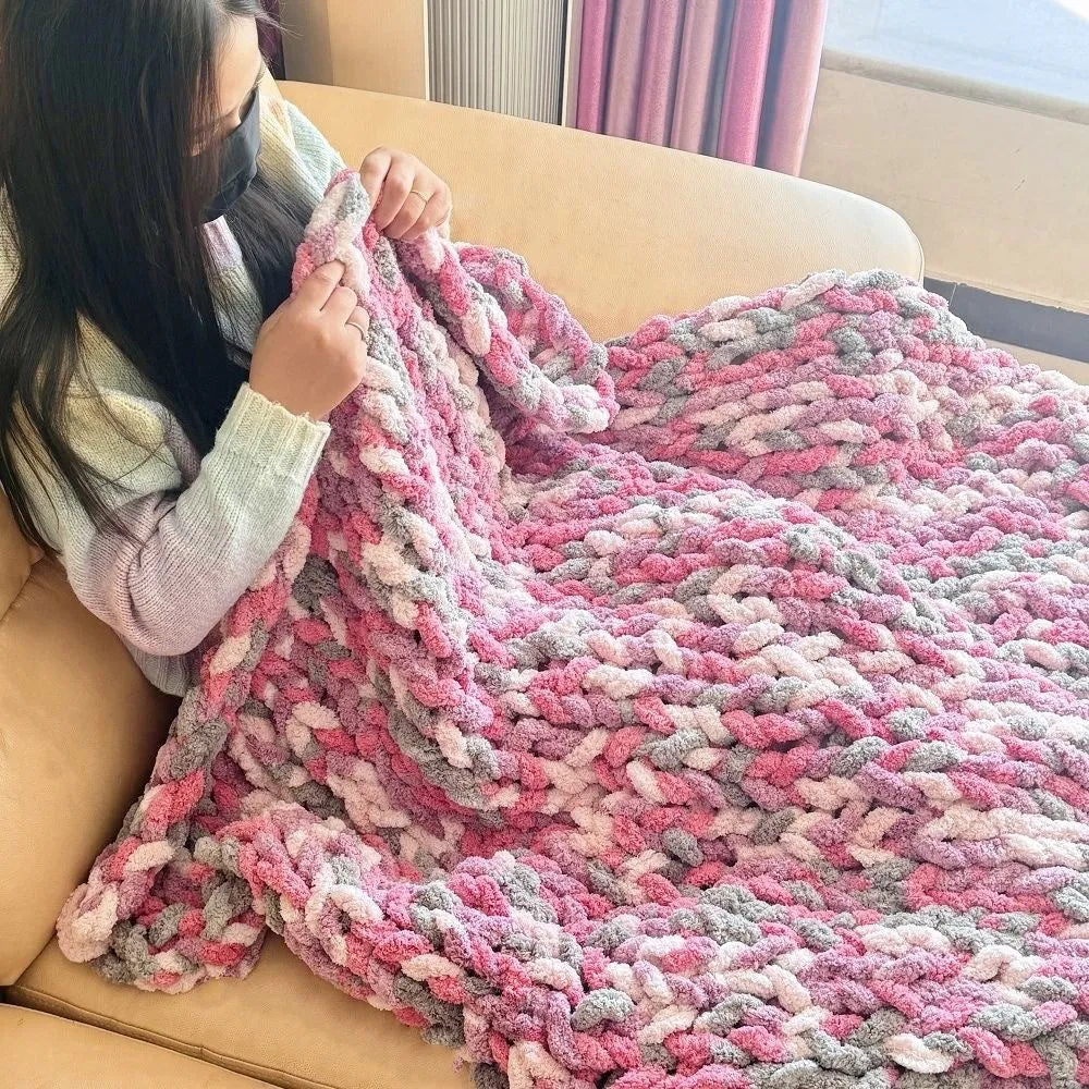 Coarse yarn chenille knitted blanket with braided gravity trim in a modern colour on a bed.