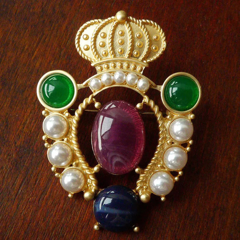 Close-up of a vintage baroque style zinc alloy brooch with a diamond shape on a dark fabric background.