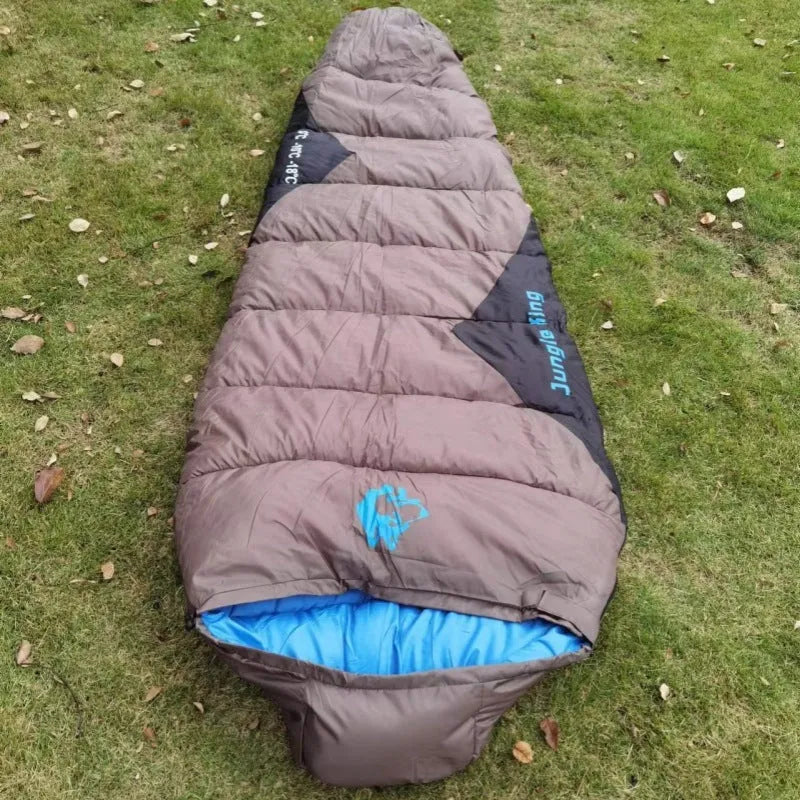 Outdoor cotton sleeping bag in army green with its compression storage bag laid alongside.