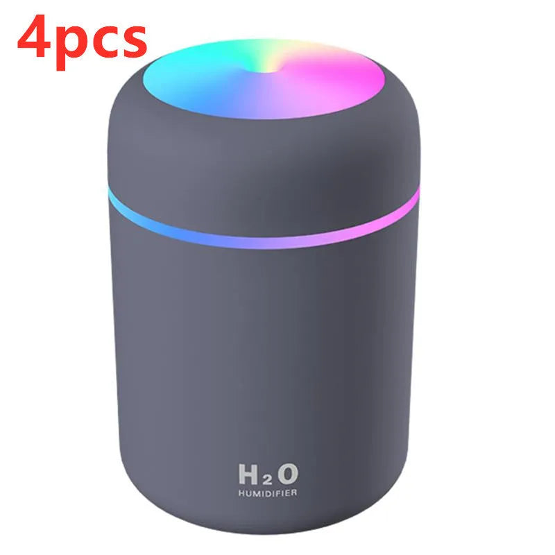 Pink USB desktop humidifier with coloured lights and water tank on a wooden desk