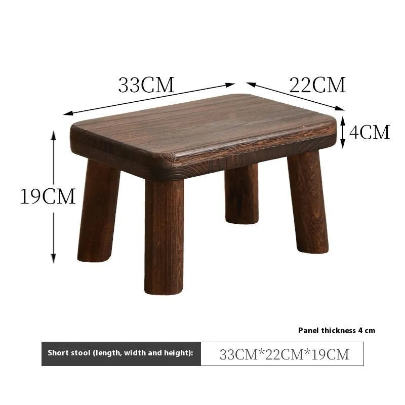 Distressed solid wood shoe changing stool with bracket structure, shown in a hallway setting.