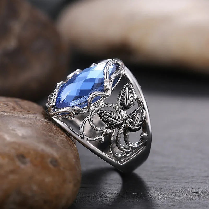 Blue crystal inlay on a geometric horse eye-shaped alloy ring for women.