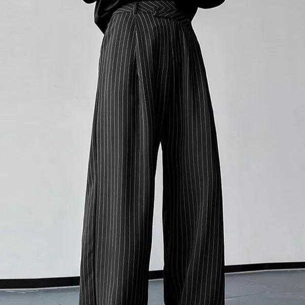Men's black vertical striped pleated casual trousers showing elastic waistband and tapered leg