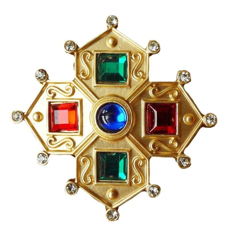Close-up of a vintage baroque style zinc alloy brooch with a diamond shape on a dark fabric background.