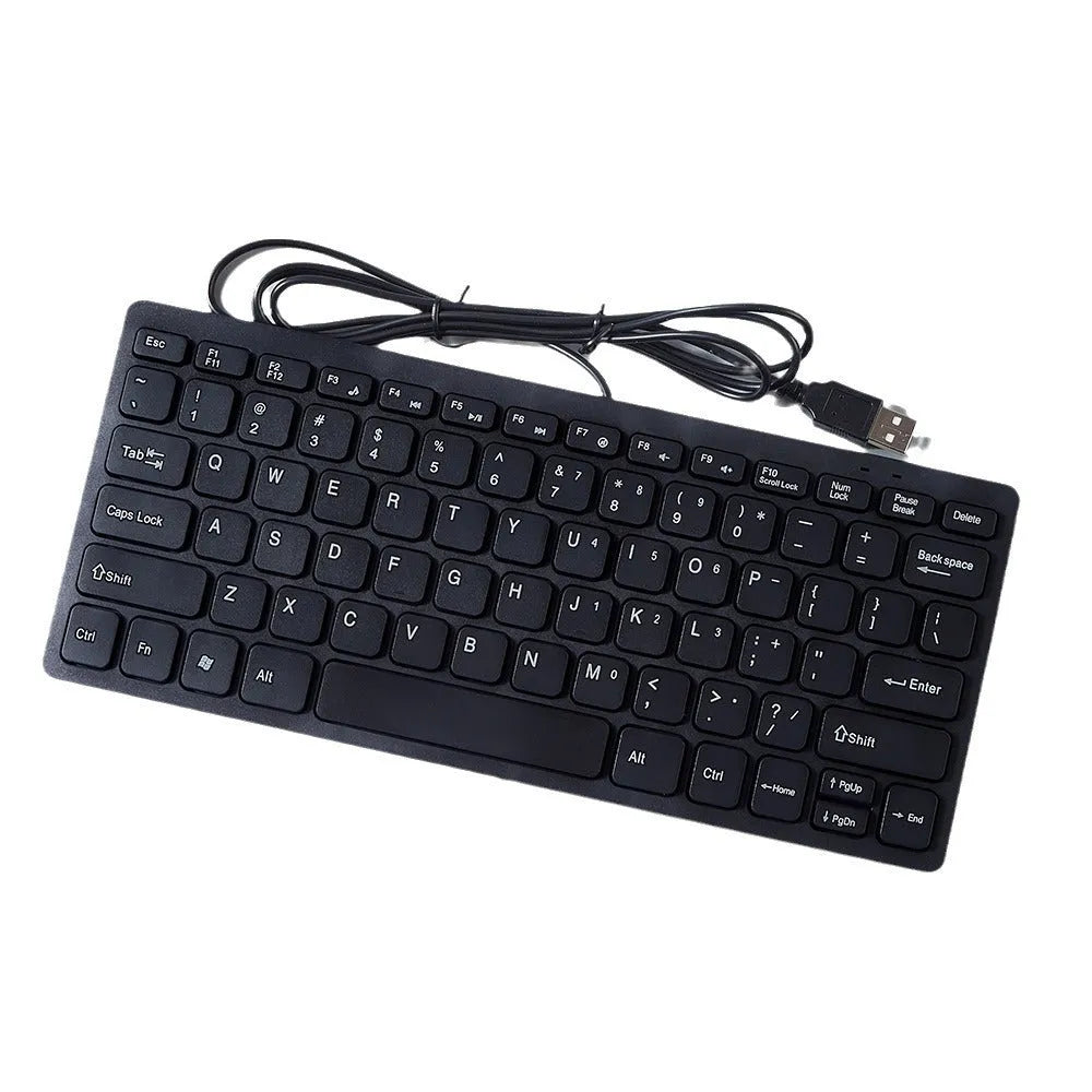 Compact black wired USB keyboard with noiseless keys next to notebook computer