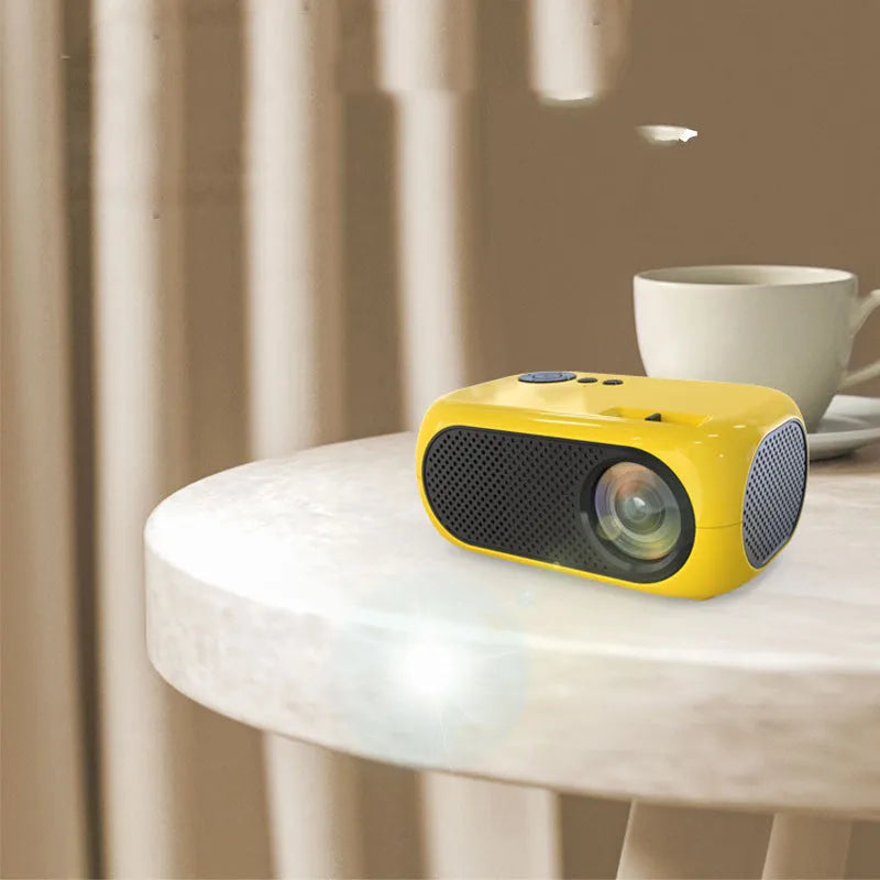 Compact gold or white M24 micro mini LED projector on a table with power adapter and AV cable.