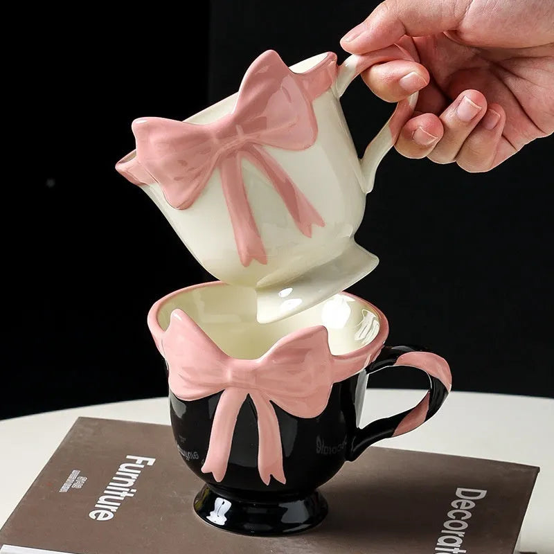 Ceramic mug with a heart and bow design in black pink and white powder colour options.
