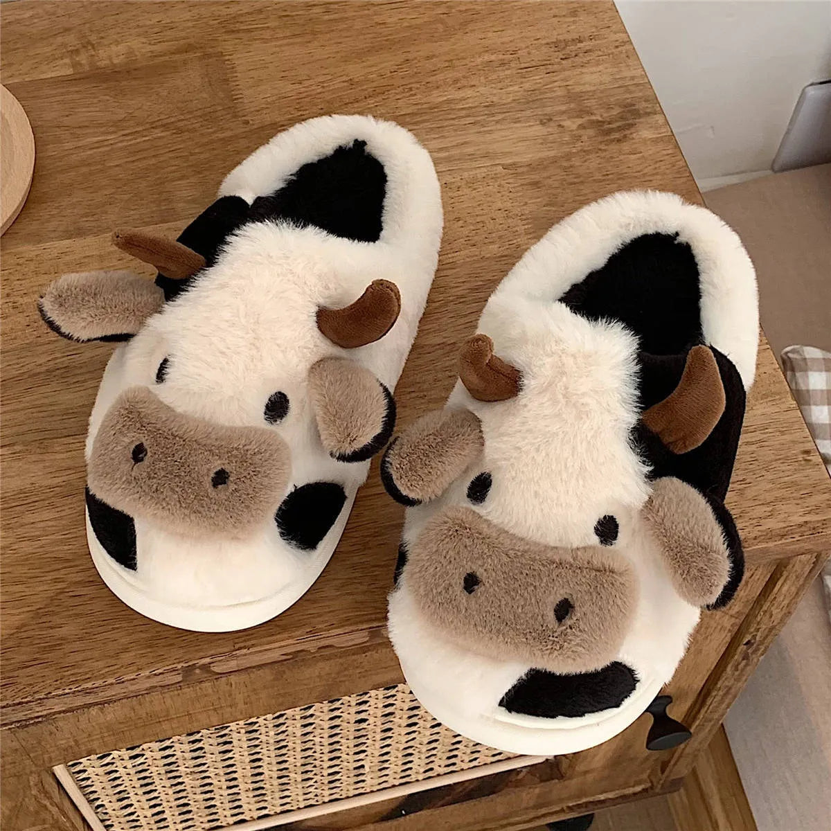 White cow-themed faux fur slippers with plush lining and textured non-slip soles.