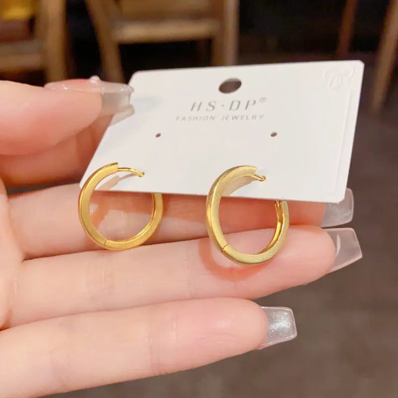Geometric gold-plated ear clip with round eyelet detail on white background