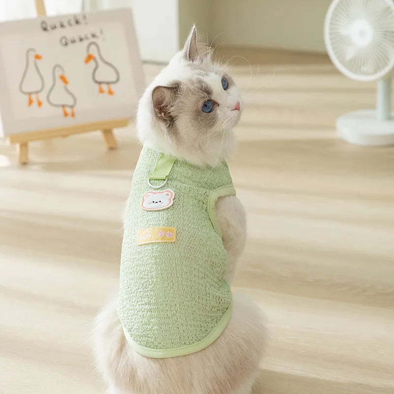 Green knitted cat clothing with a bear patch, showing hollowed-out breathable knit fabric.