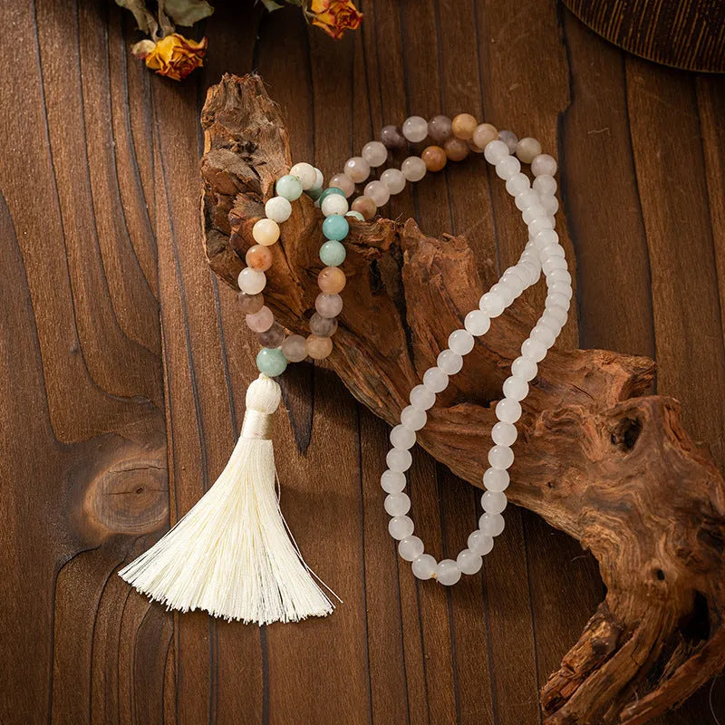 Long natural stone beaded sweater chain necklace and matching bracelet in bohemian style on a grey background.