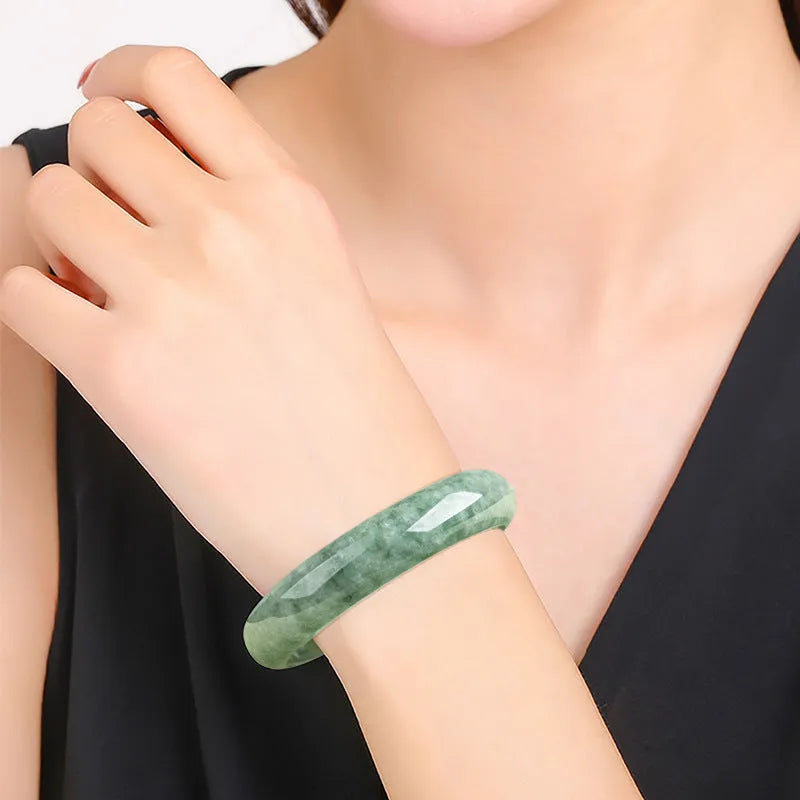 Natural emerald bean green bracelet on wrist, showing simple band and deep green gemstone.
