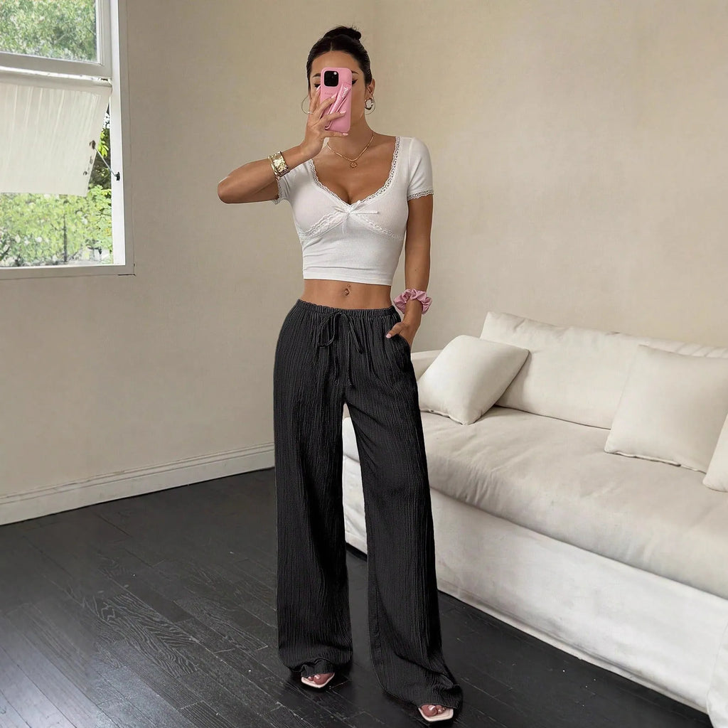 Women's black wide leg trousers with lace-up waist detail showing adjustable fit feature