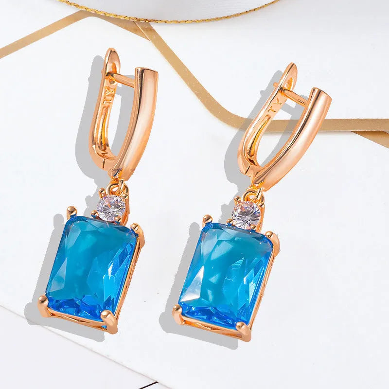 A pair of square-shaped gold-coloured geometric earrings on a white background.