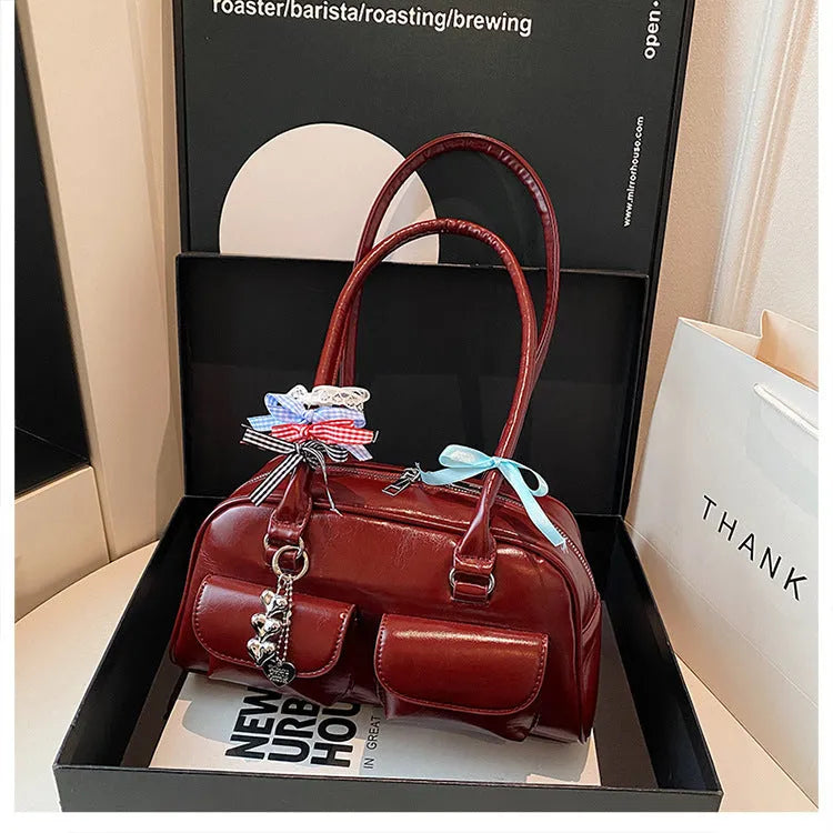 Retro women's black PU leather pillow-shaped shoulder bag with flap and double straps, shown with optional ribbon pendant.