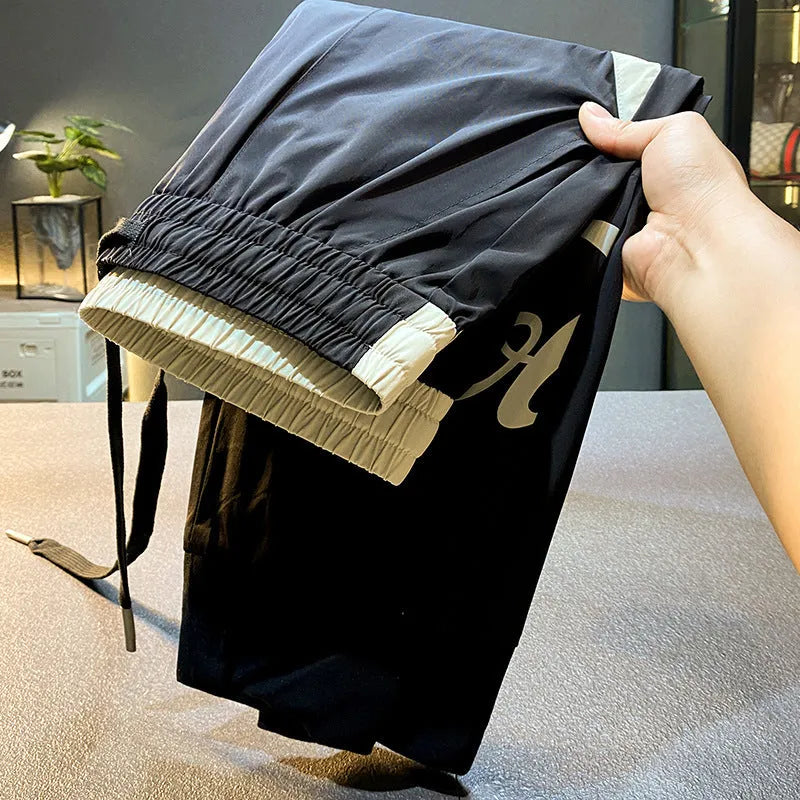 Men's black cropped trousers with ankle banding in ultra-thin ice silk fabric laid flat to show casual design.