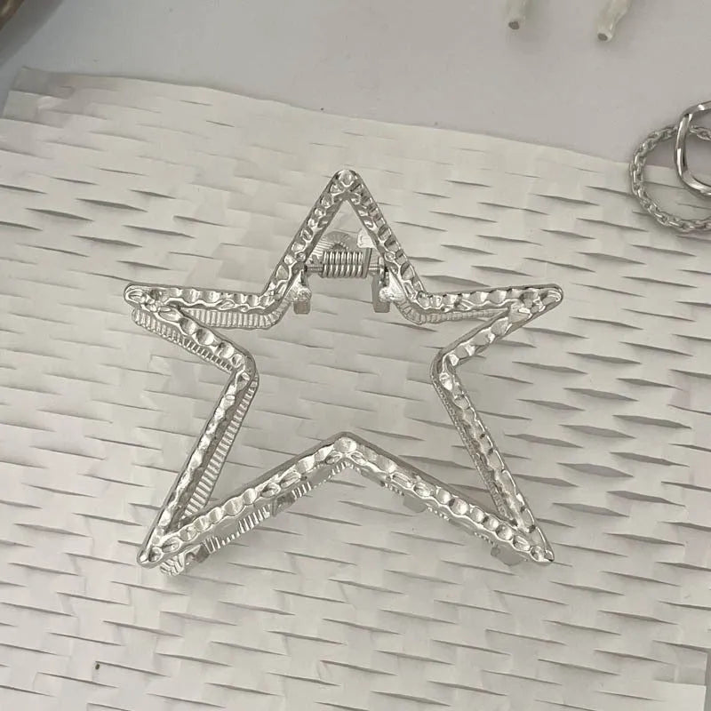 Assortment of silver metal hair claw barrettes with various designs including bows, pearls, and geometric shapes.