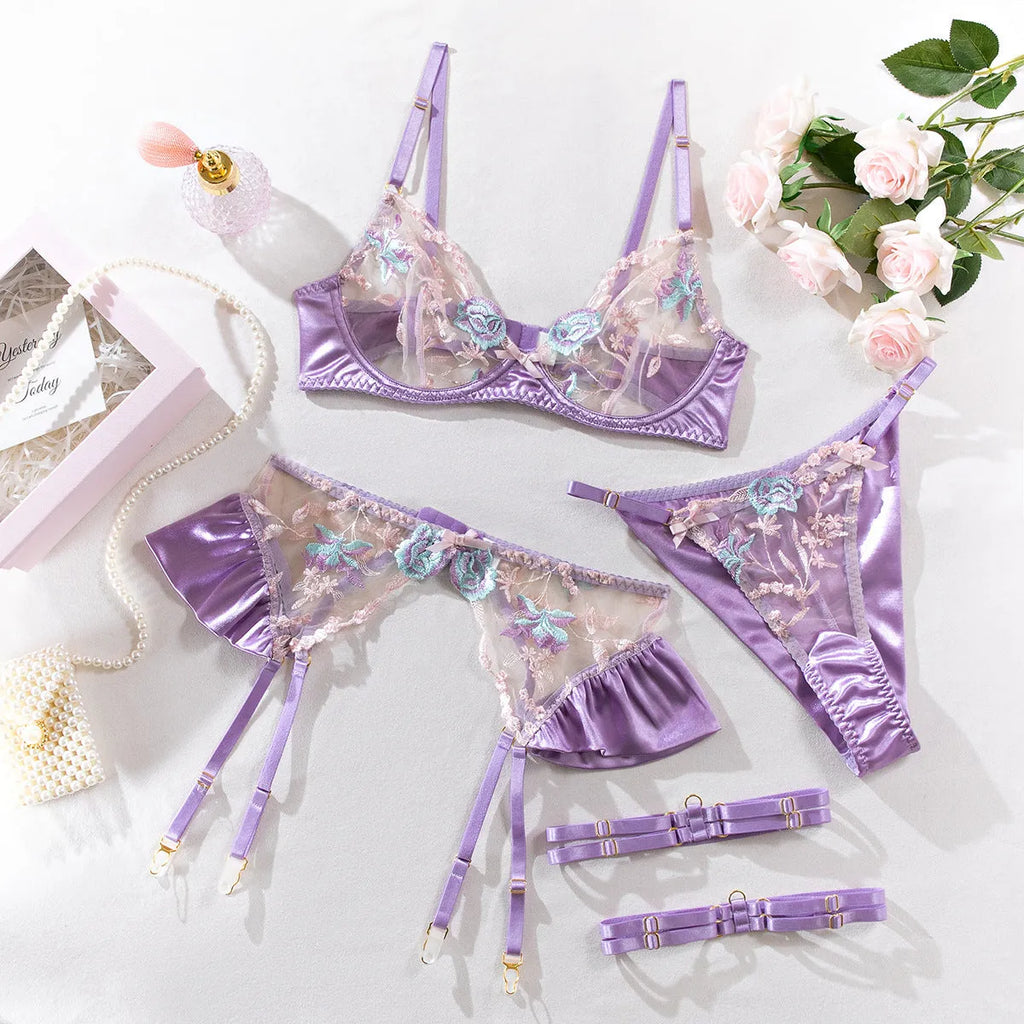 Light purple satin four-piece lingerie set laid flat, showing the three-point style and delicate fabric texture.