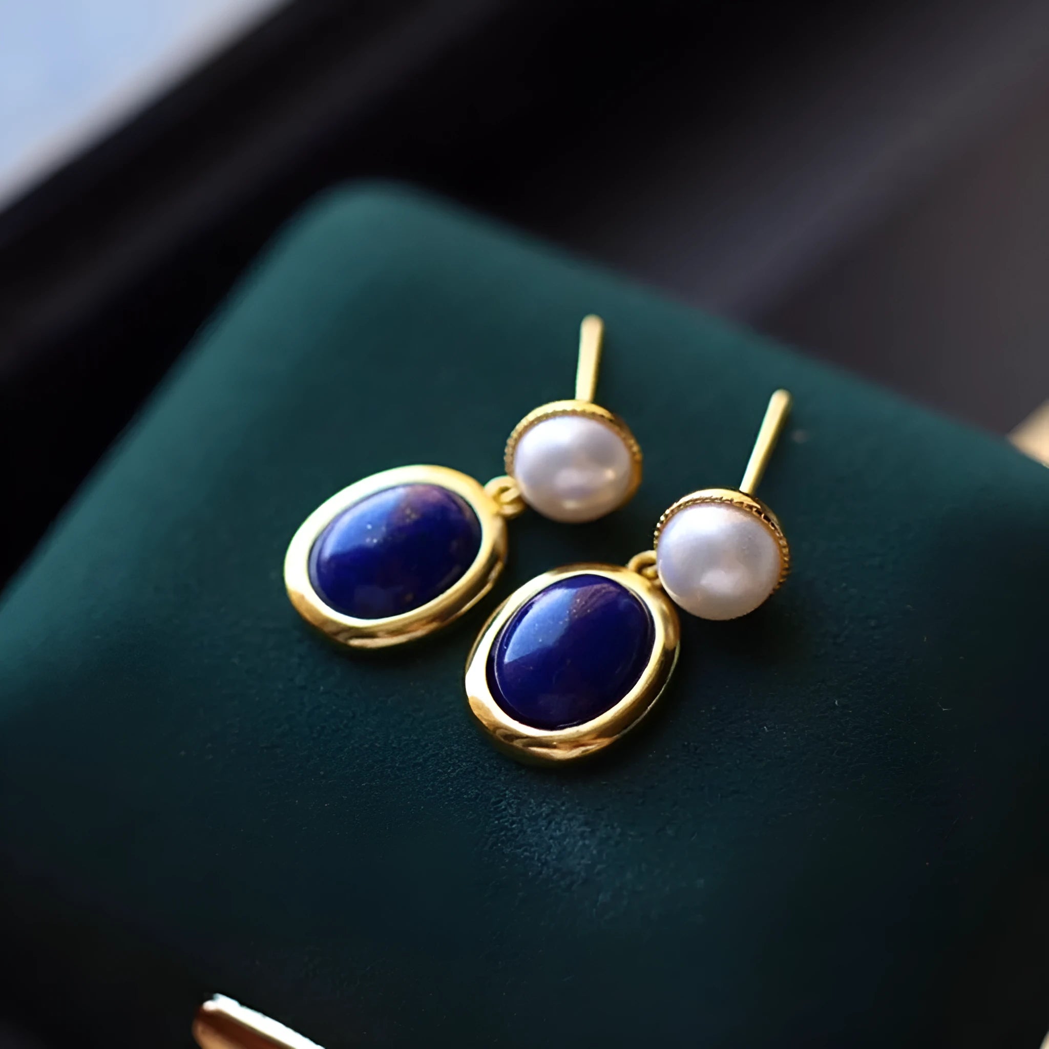 A pair of simple stud earrings with a blue lapis lazuli pearl set in a sterling silver setting.