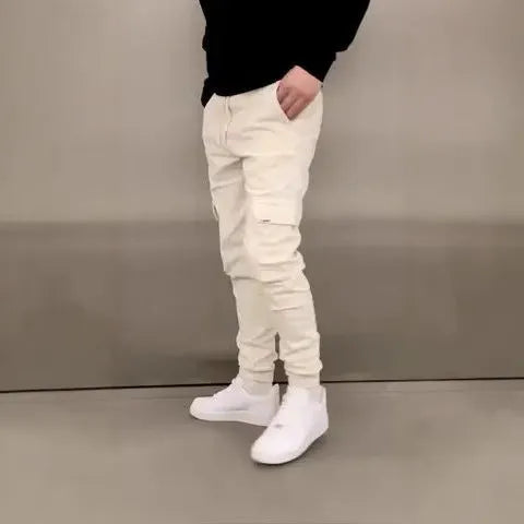 Man wearing loose light blue casual trousers with patch pockets and an elasticated waist.