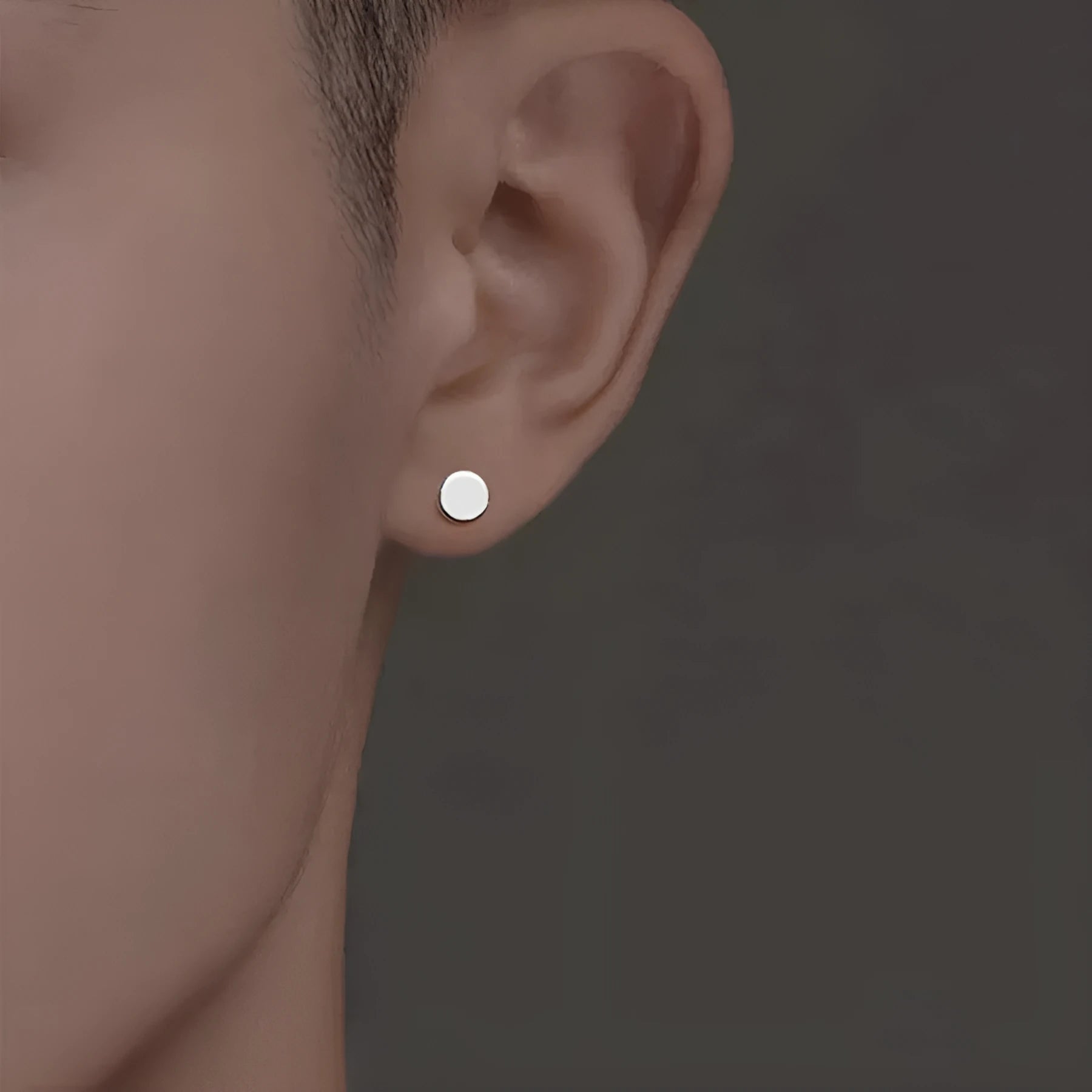 A pair of simple round S999 sterling silver flat ear bone studs on a plain background.
