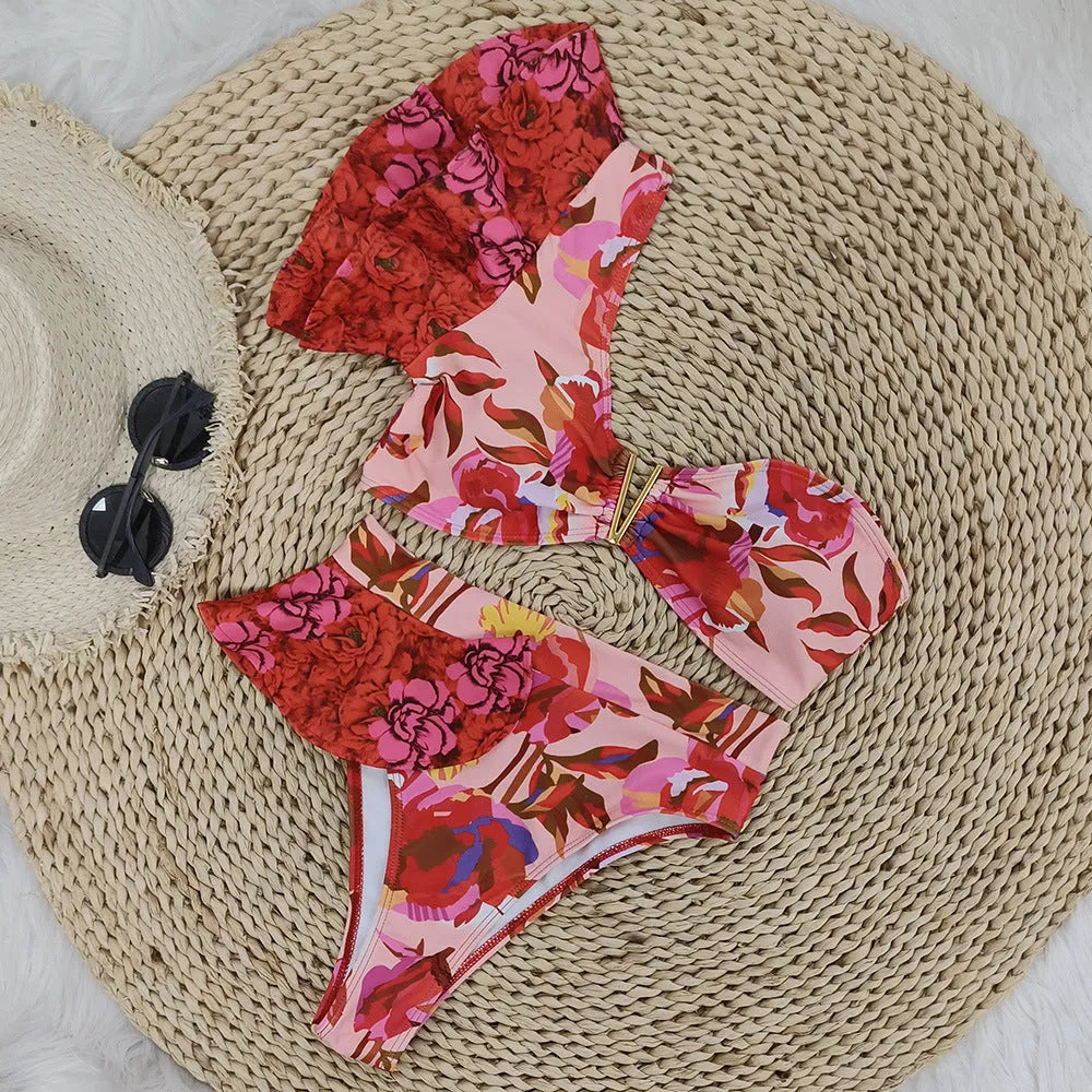 Red floral print on pink women's one-shoulder ruffled bikini with high-waist bottoms.