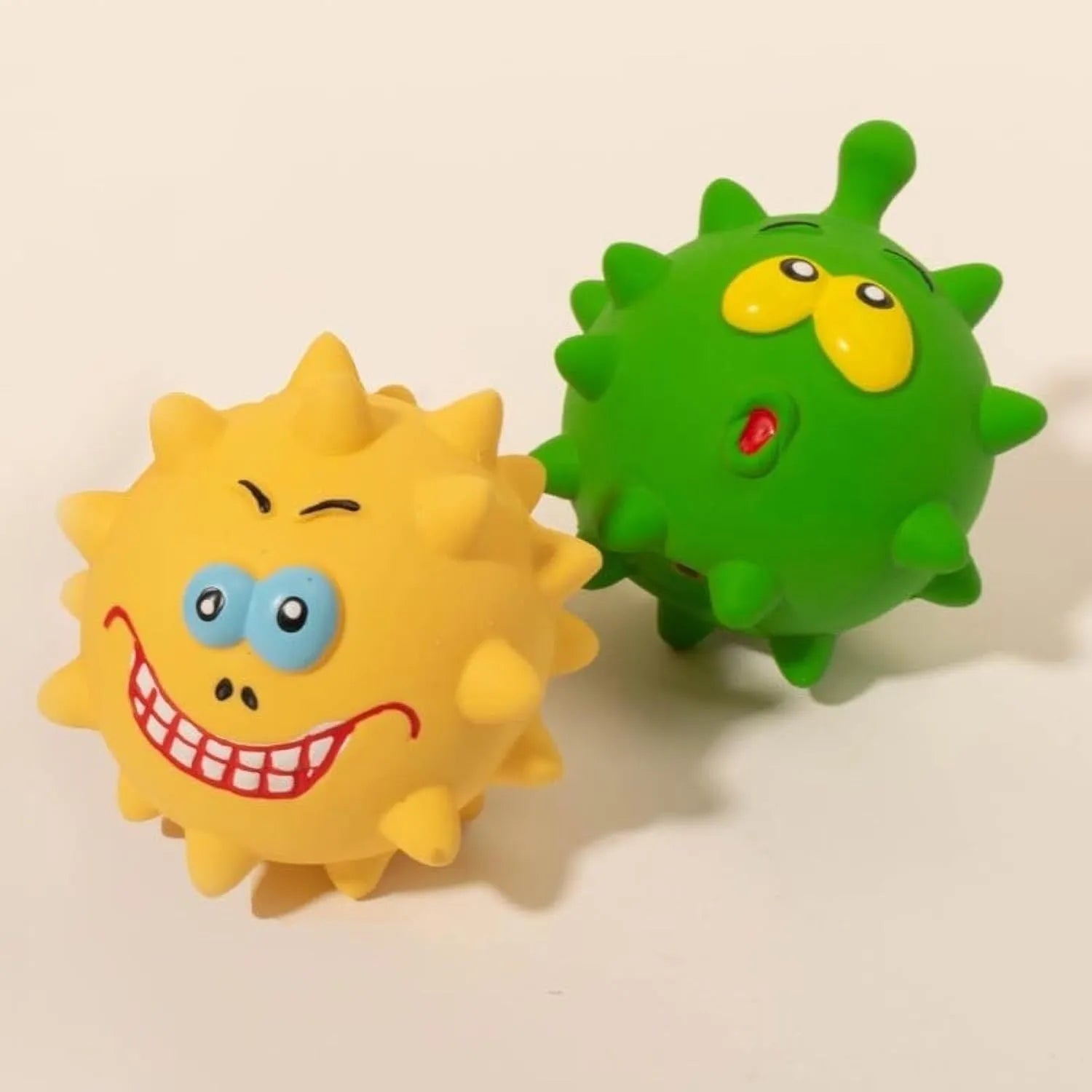 Four colourful squeaky dog balls with cute faces on natural latex rubber with bumpy dental-cleaning surface