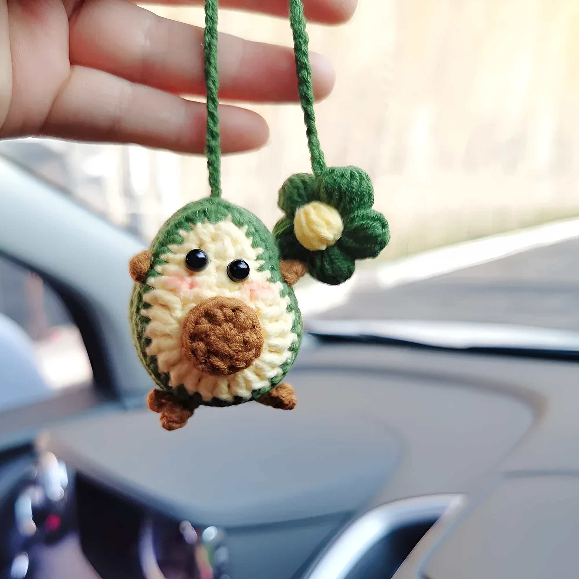 Handmade crocheted avocado flower car pendant in wool with rainbow colours hanging in vehicle