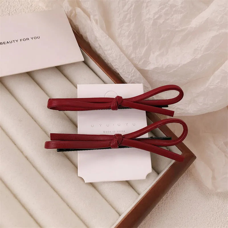 Wine red leather bow-shaped hair barrette on a white background.