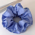 Blue striped fabric ball large intestine style stretch hairband on neutral background