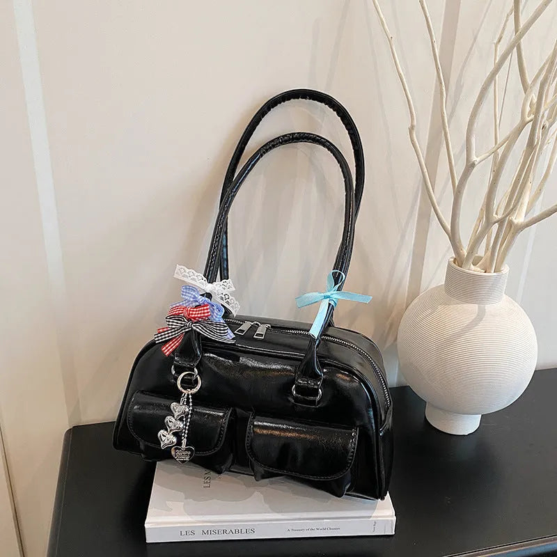 Retro women's black PU leather pillow-shaped shoulder bag with flap and double straps, shown with optional ribbon pendant.