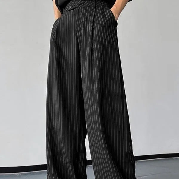 Men's black vertical striped pleated casual trousers showing elastic waistband and tapered leg