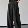 Men's black vertical striped pleated casual trousers showing elastic waistband and tapered leg