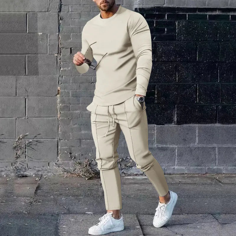 Man wearing a light grey round-neck long-sleeve t-shirt and matching trousers from a two-piece polyester suit set.