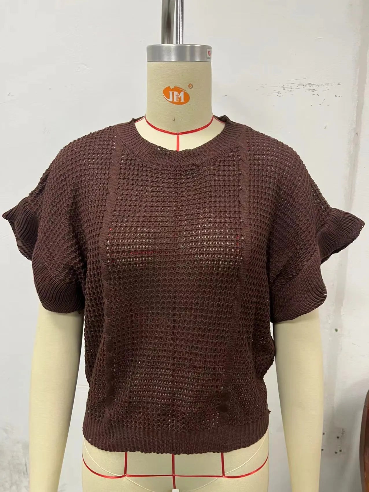 Loose-fitting white knitted pullover sweater with textured ruffled short sleeves on a model.