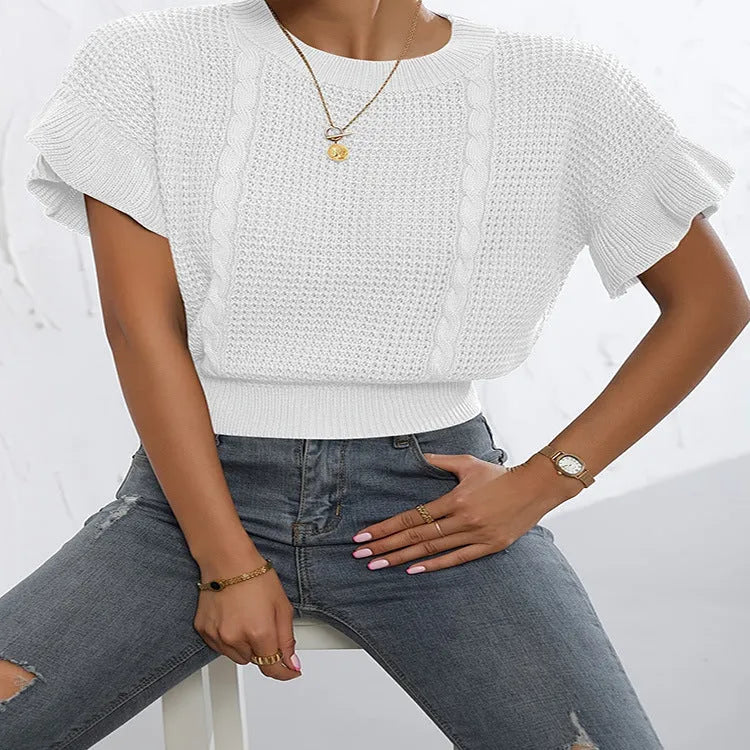 Loose-fitting white knitted pullover sweater with textured ruffled short sleeves on a model.