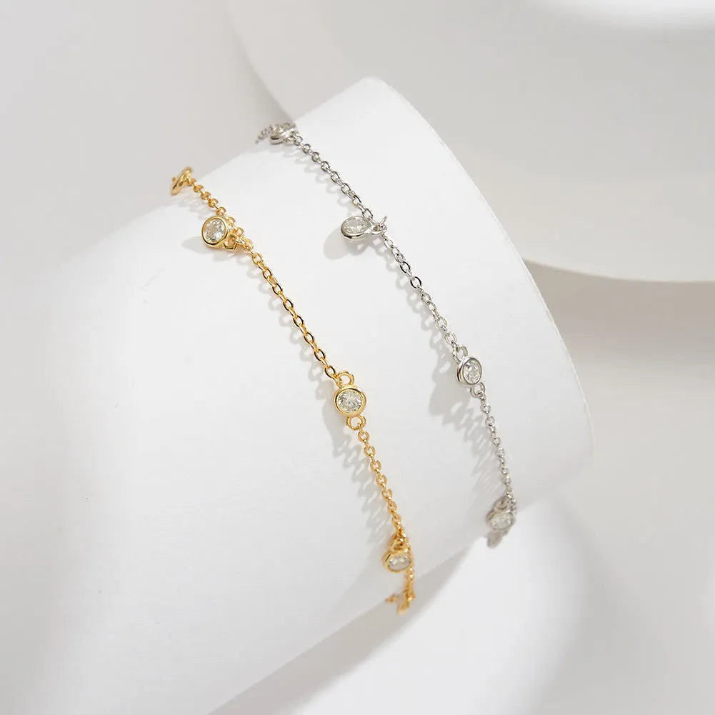 Close-up of a women's silver anklet with a small geometric zirconium pendant on a fine, adjustable chain.