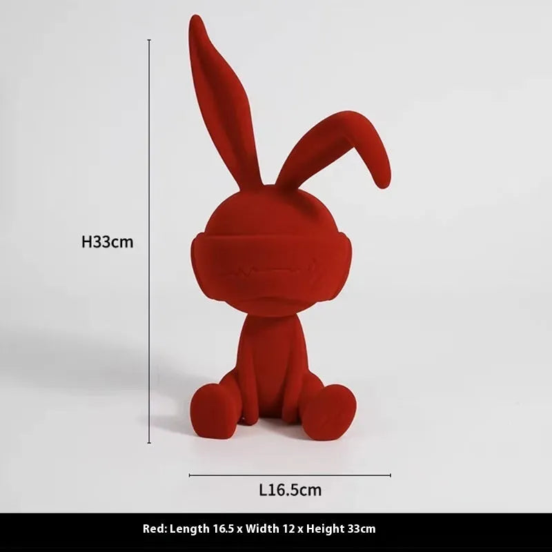 Suede blindfold rabbit resin table ornament in blue, green, or red colour on a shelf.